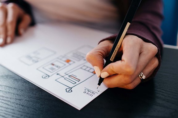 Person sketching out wireframes and user goals for UX design