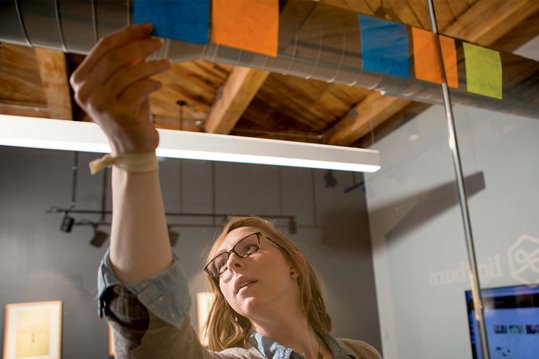A UX designer using sticky notes on a conference room window for design planning