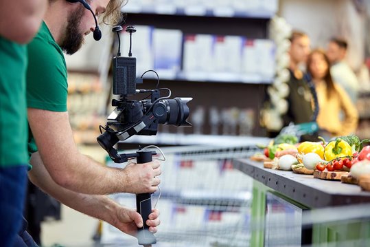 cameraman shooting video of fresh produce while producer and client look on
