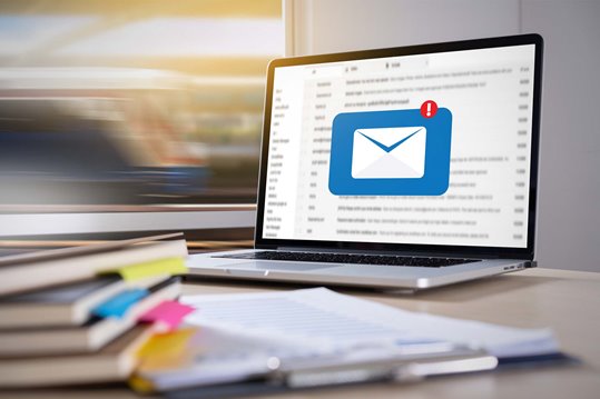 Large email icon overlaying an email inbox on a desktop 