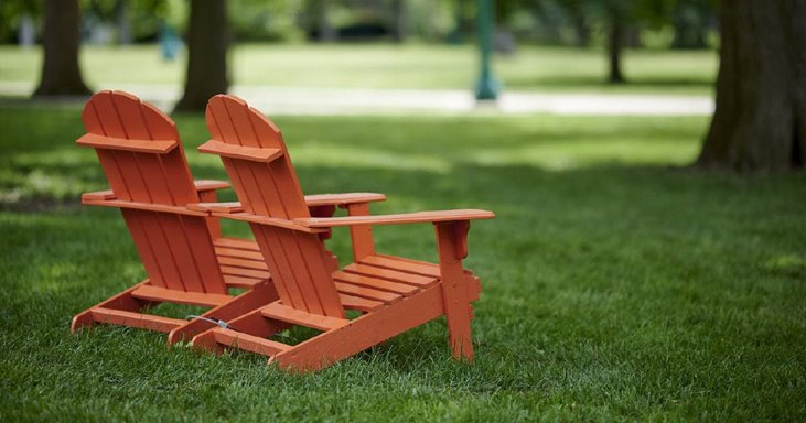 A pair of Adirondack chairs in a yard.