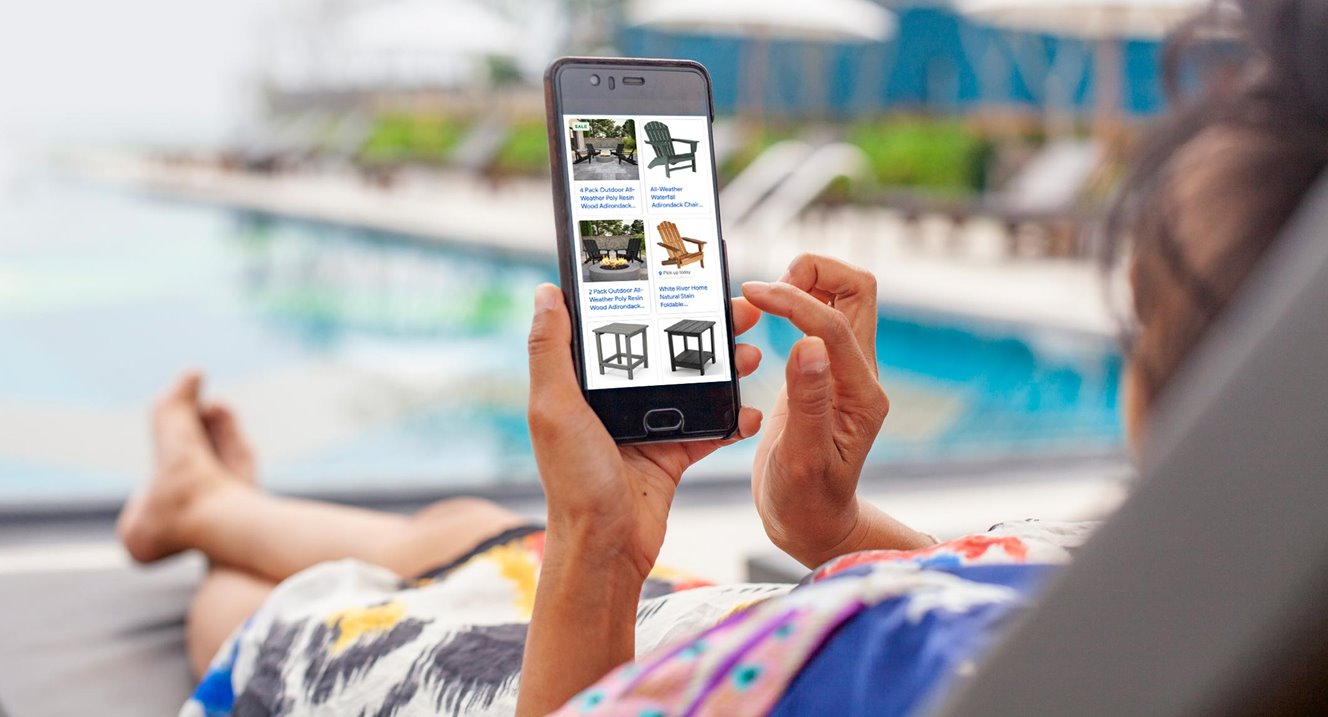 Person relaxing near a pool, shopping on their phone 