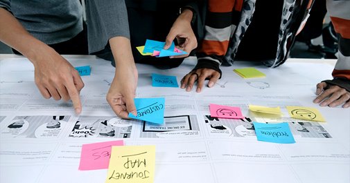 People using sticky notes to create a flow chart for market research and user design.