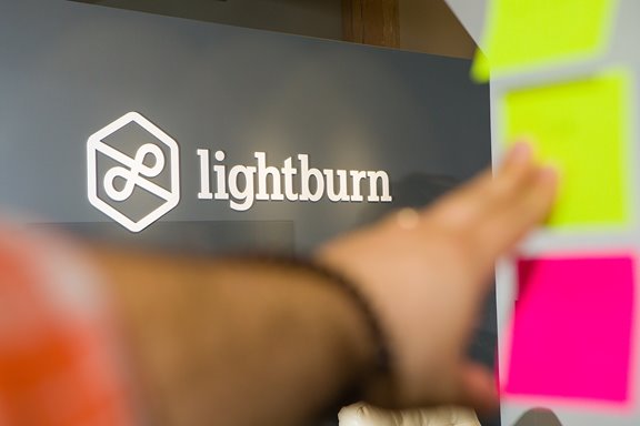 A picture of the Lightburn logo through glass with employee in the foreground. 