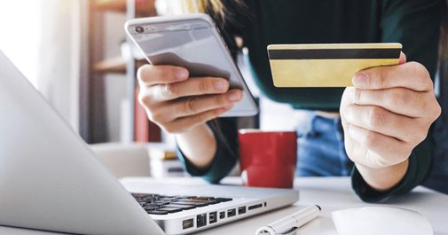 A person using their phone and credit card to purchase something within a mobile Ecommerce experience. 