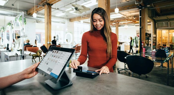 Woman checking out at a counter using credit card reader