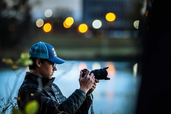 photographer checking his camera at twilight in the middle of a photography shoot