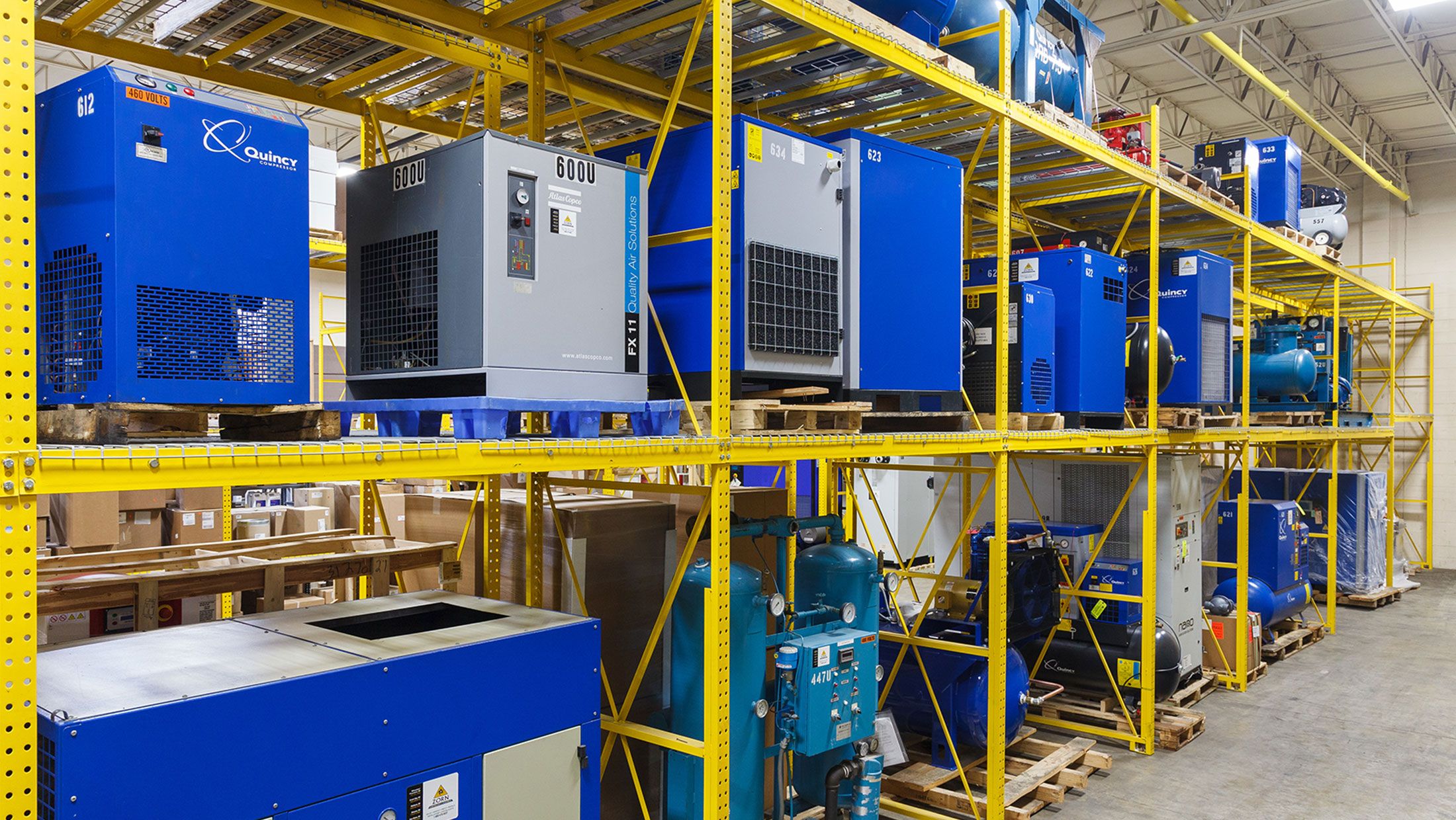 Rows of blue and gray industrial air compressors stocked on warehouse shelving at Zorn.